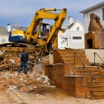 A large backhoe demolishes an old building