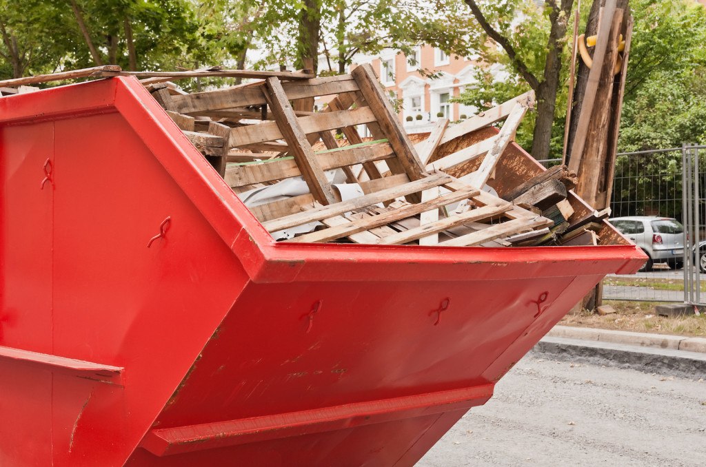 Grosser roter Container aus Metall mit Holz-Abfall